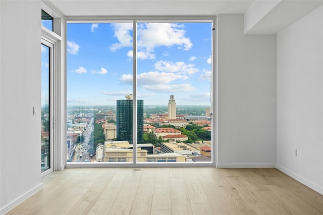 313 W 17th St Unit 2403, Austin, TX 78701 - empty room featuring a city view, wood finished floors, floor to ceiling windows, and baseboards