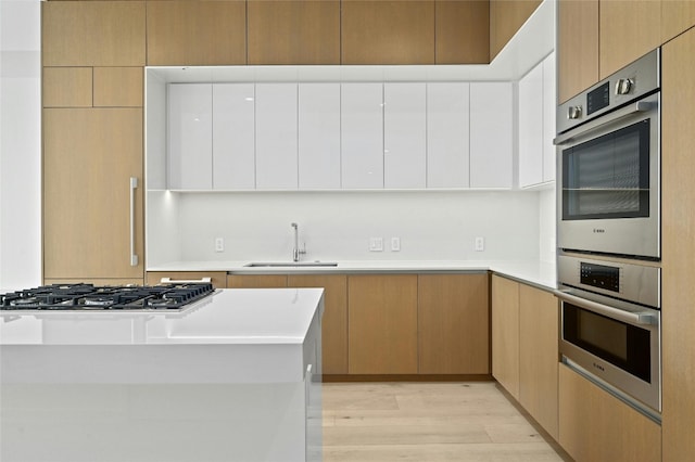 313 W 17th St Unit 2403, Austin, TX 78701 - kitchen with light countertops, white cabinetry, light wood-style floors, modern cabinets, and appliances with stainless steel finishes