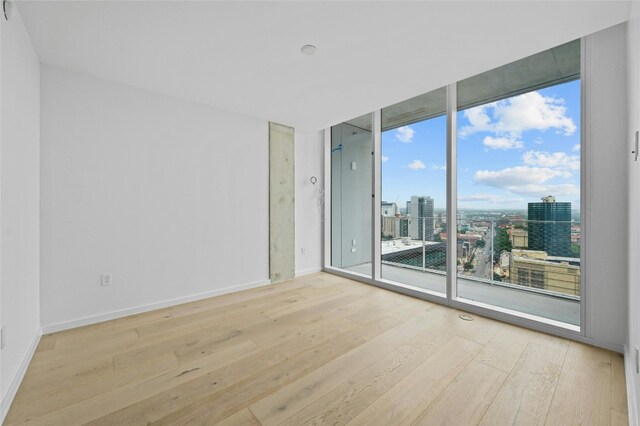 313 W 17th St Unit 2403, Austin, TX 78701 - unfurnished room featuring floor to ceiling windows, a city view, wood-type flooring, and baseboards
