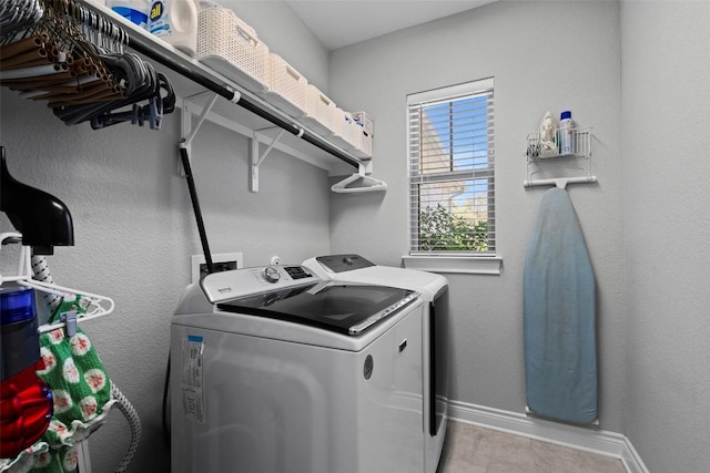 clothes washing area with washing machine and clothes dryer and baseboards