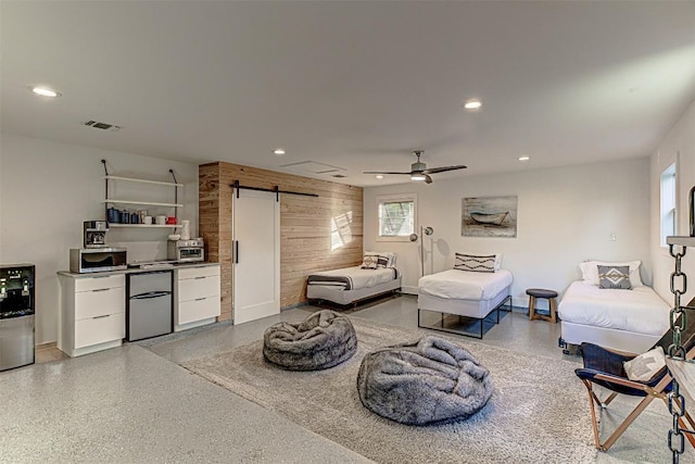living area featuring a barn door, recessed lighting, ceiling fan, dark aggregate flooring, and baseboards