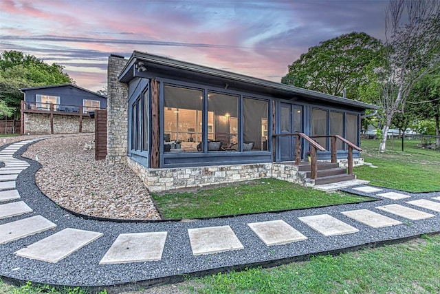rear view of property featuring a sunroom and a yard