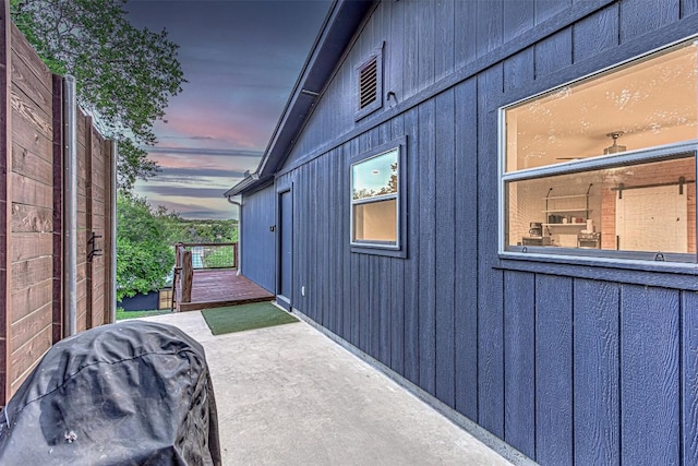 patio terrace at dusk featuring area for grilling and a wooden deck