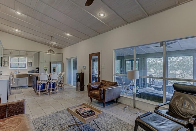 living area featuring lofted ceiling, plenty of natural light, light tile patterned flooring, a ceiling fan, and recessed lighting