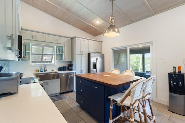kitchen with appliances with stainless steel finishes, lofted ceiling, butcher block countertops, a sink, and light tile patterned floors