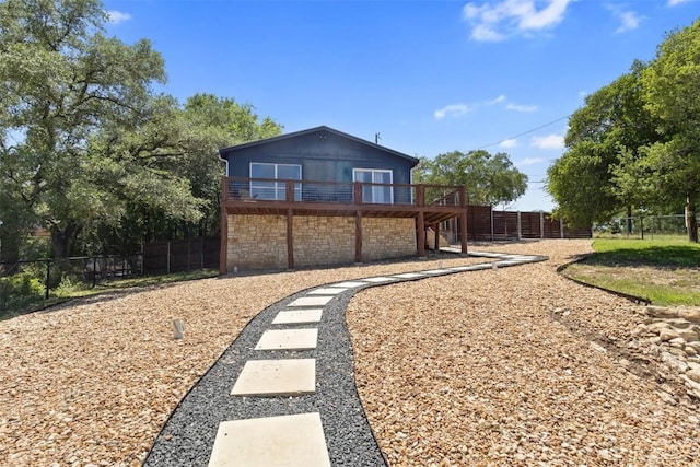 back of property with a deck, fence, and stone siding