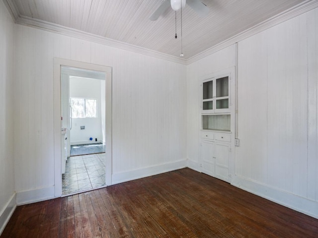 empty room featuring dark wood-type flooring, ceiling fan, baseboards, and ornamental molding