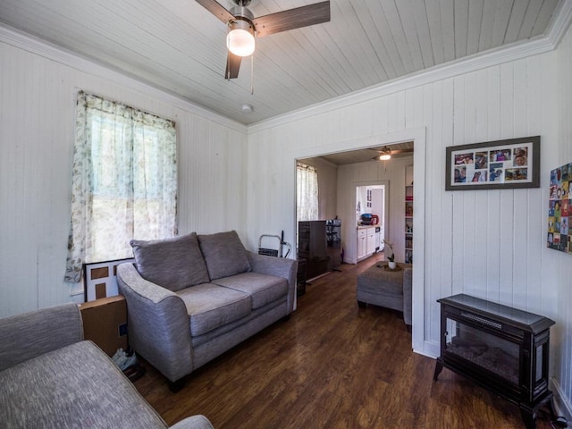 living area featuring a wood stove, ornamental molding, ceiling fan, and wood finished floors