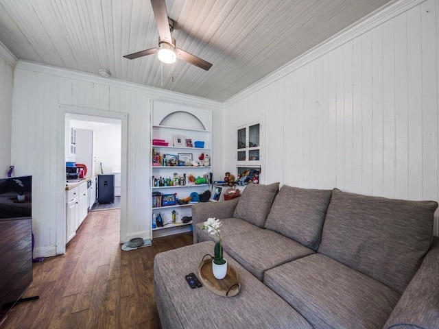 living area featuring built in features, ceiling fan, dark wood-type flooring, ornamental molding, and wooden walls