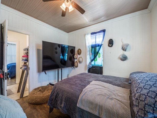 bedroom featuring crown molding, wood walls, ceiling fan, and wood finished floors