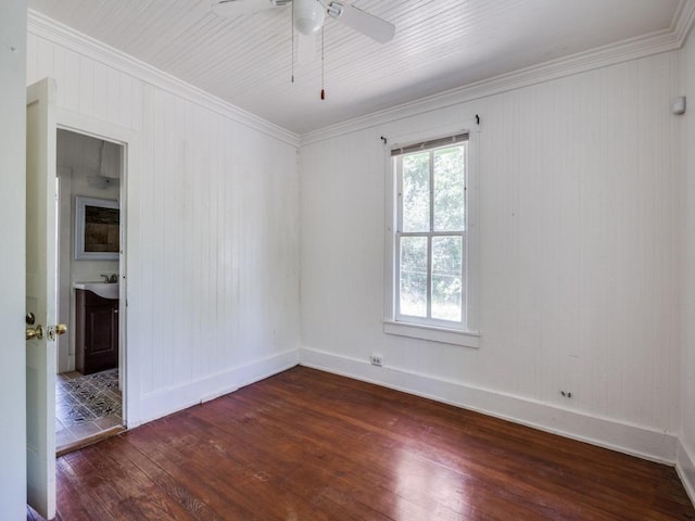 spare room with crown molding, dark wood finished floors, a ceiling fan, a sink, and baseboards