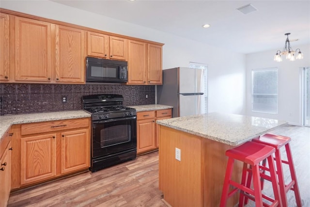 2025 Wayward Sun Dr, Austin, TX 78754 - kitchen featuring black appliances, light wood-style flooring, tasteful backsplash, light stone countertops, and a kitchen bar