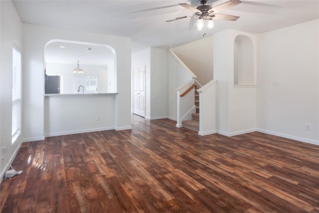 2025 Wayward Sun Dr, Austin, TX 78754 - unfurnished living room with dark wood-style floors, stairs, ceiling fan, and arched walkways