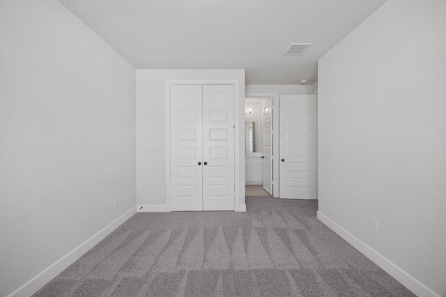 unfurnished bedroom with a closet, carpet flooring, visible vents, and baseboards