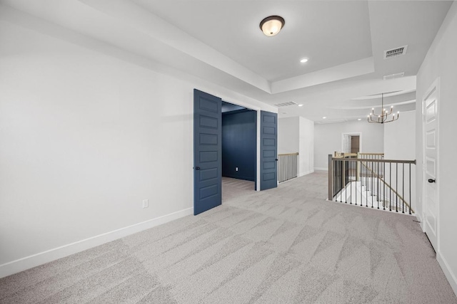 carpeted spare room featuring an inviting chandelier, a tray ceiling, visible vents, recessed lighting, and baseboards