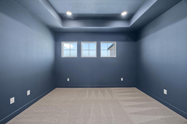 carpeted spare room featuring baseboards and a raised ceiling