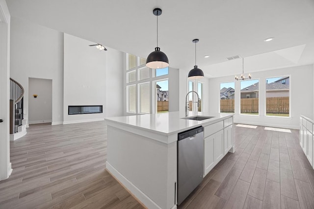 kitchen with baseboards, light wood-style floors, visible vents, dishwasher, and a sink
