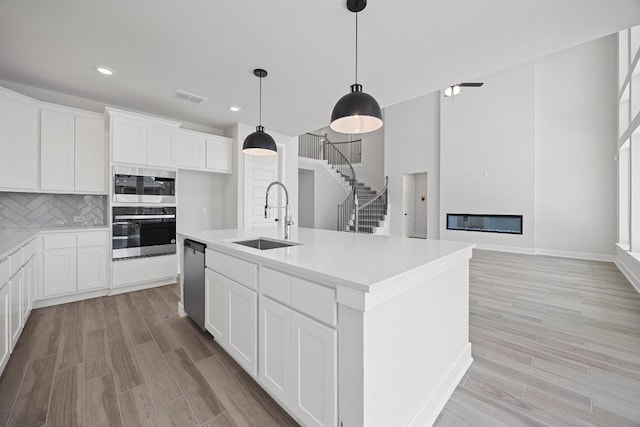kitchen featuring stainless steel appliances, light wood finished floors, visible vents, and a sink