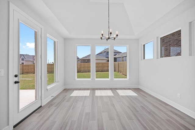 unfurnished dining area featuring baseboards, light wood finished floors, and a chandelier