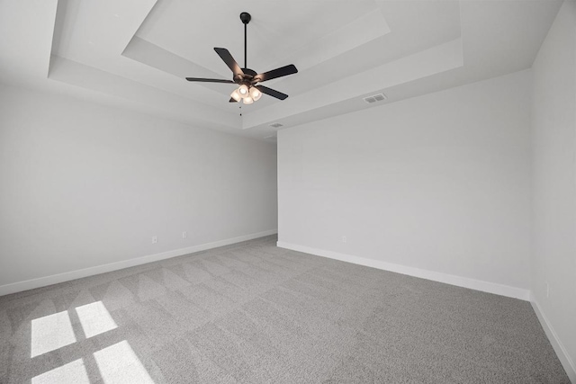 spare room with visible vents, carpet floors, and a raised ceiling