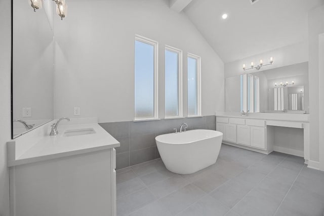 full bathroom with a freestanding bath, a sink, two vanities, vaulted ceiling with beams, and tile patterned flooring