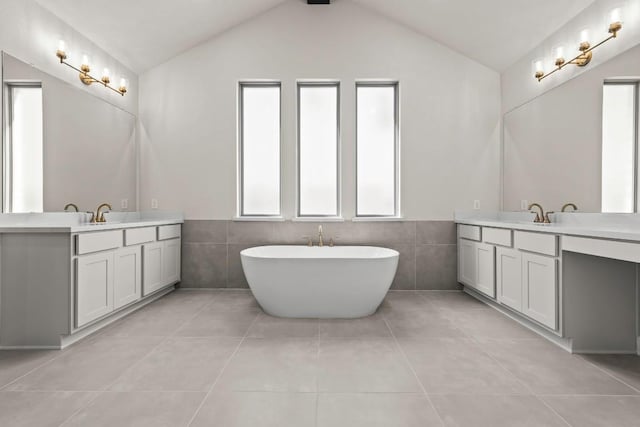 212 Ranchland Pass, Liberty Hill, TX 78642 - bathroom featuring tile walls, tile patterned floors, vaulted ceiling, two vanities, and a soaking tub