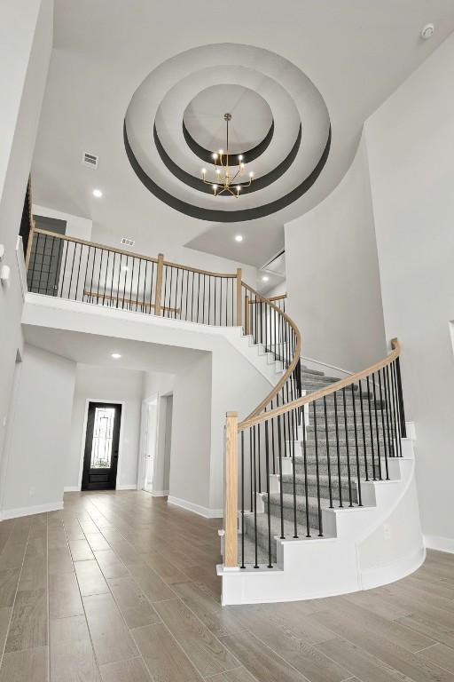 212 Ranchland Pass, Liberty Hill, TX 78642 - stairway with a high ceiling, a raised ceiling, a chandelier, wood finished floors, and recessed lighting