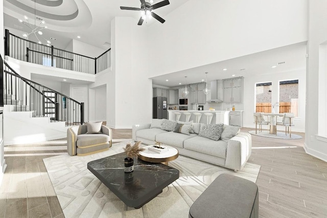 212 Ranchland Pass, Liberty Hill, TX 78642 - living room featuring a towering ceiling, stairway, light wood-style floors, baseboards, and ceiling fan