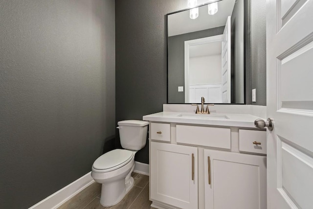 212 Ranchland Pass, Liberty Hill, TX 78642 - half bath featuring vanity, toilet, wood finished floors, baseboards, and a textured wall