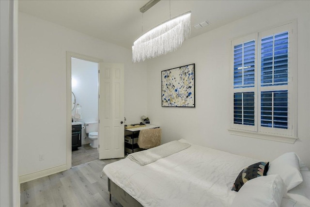 bedroom featuring ensuite bathroom, baseboards, and wood finished floors