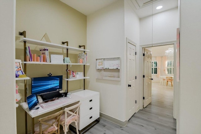 office with a high ceiling, baseboards, light wood finished floors, and attic access