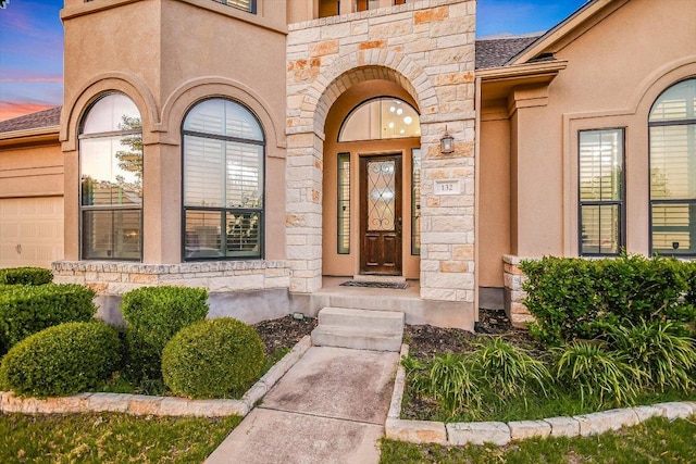 entrance to property featuring stucco siding and stone siding
