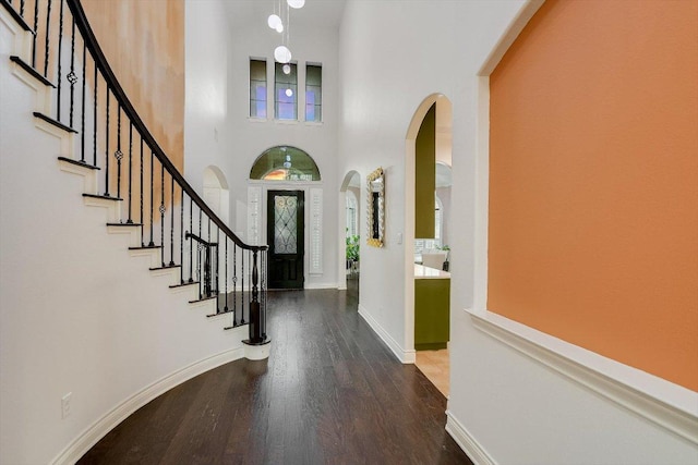 foyer featuring baseboards, stairs, wood finished floors, and a towering ceiling