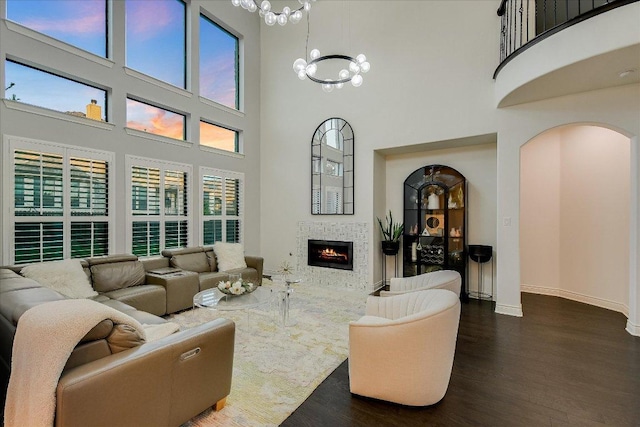 living room featuring a high ceiling, arched walkways, wood finished floors, and a chandelier