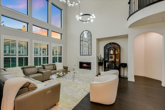 132 Archipelago Trl, Austin, TX 78717 - living area featuring wood finished floors, a chandelier, a towering ceiling, arched walkways, and a tile fireplace