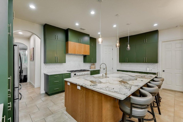 kitchen with arched walkways, a sink, light tile patterned flooring, and green cabinets