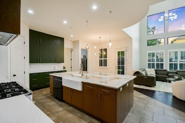 kitchen featuring black dishwasher, tile patterned floors, a sink, backsplash, and decorative light fixtures