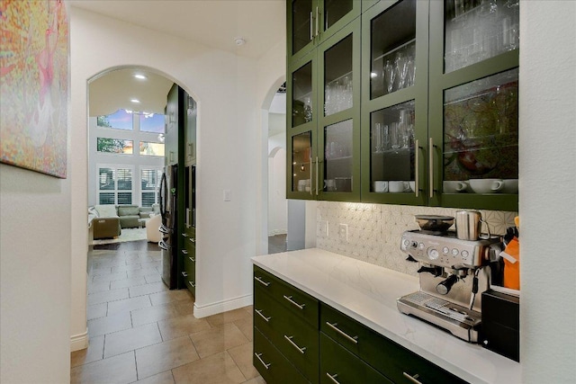 bar with arched walkways, baseboards, decorative backsplash, and light tile patterned floors