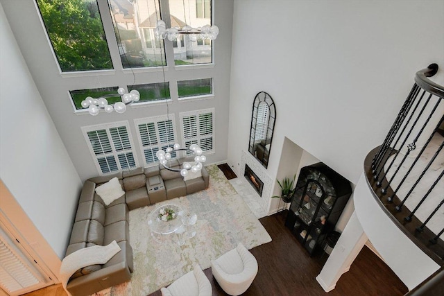 living room featuring a high ceiling, an inviting chandelier, plenty of natural light, and wood finished floors