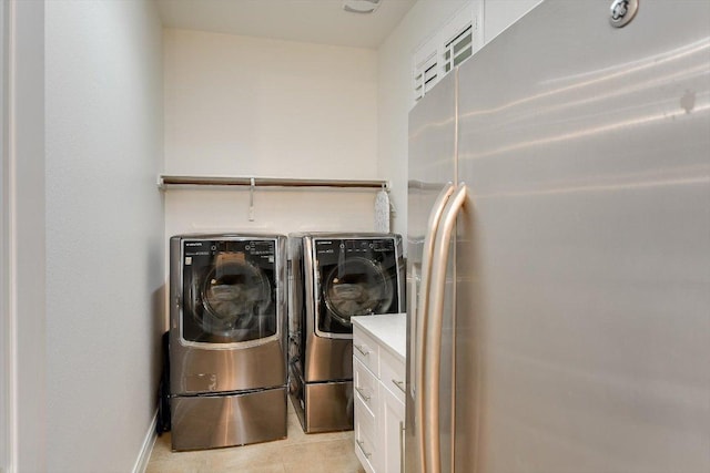washroom with light tile patterned floors, baseboards, cabinet space, and independent washer and dryer