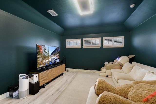 living room featuring baseboards, visible vents, wood finished floors, and lofted ceiling