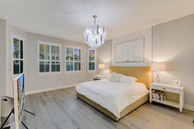 bedroom with light wood-style floors, baseboards, and a notable chandelier