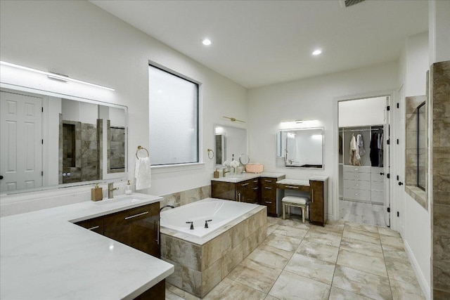 bathroom featuring a spacious closet, a tile shower, a garden tub, and vanity