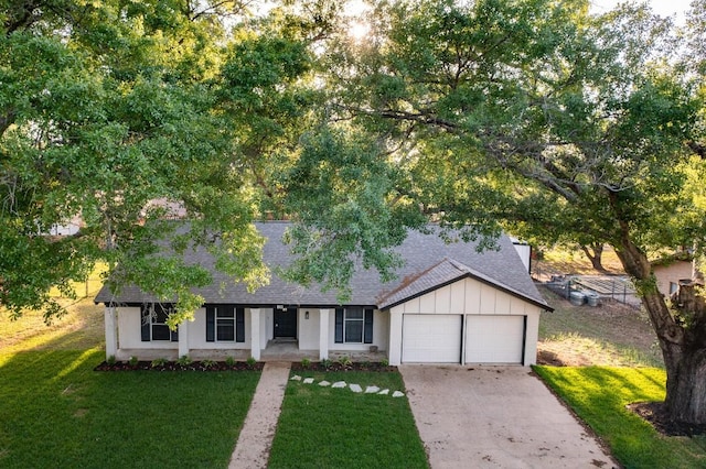 ranch-style home with a shingled roof, a garage, concrete driveway, and a front lawn