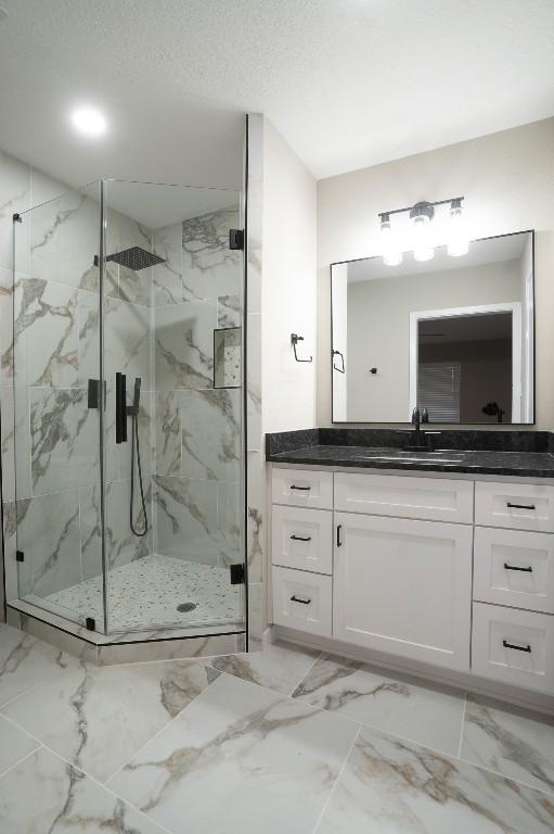bathroom with a marble finish shower, marble finish floor, and vanity