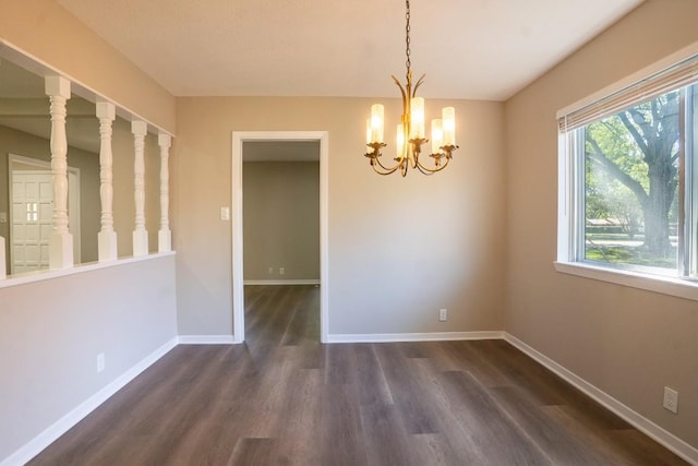 unfurnished dining area with dark wood-style flooring, baseboards, and a chandelier