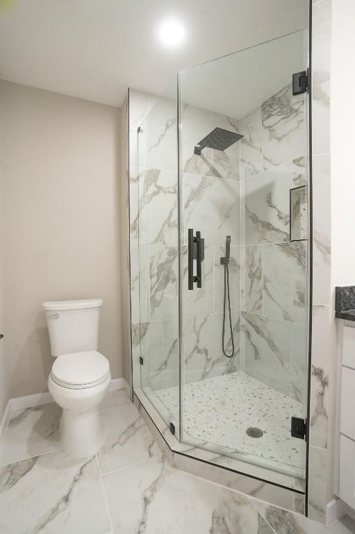 full bathroom with a marble finish shower, baseboards, marble finish floor, and toilet