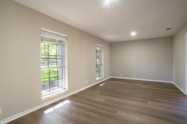 unfurnished room featuring a healthy amount of sunlight, baseboards, and dark wood finished floors