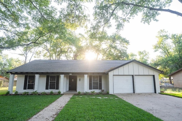 ranch-style home featuring concrete driveway, a front yard, roof with shingles, and an attached garage