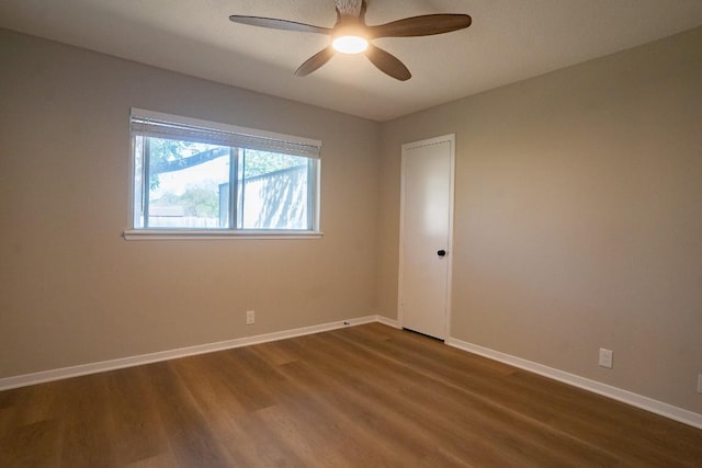 unfurnished room featuring baseboards, a ceiling fan, and dark wood finished floors